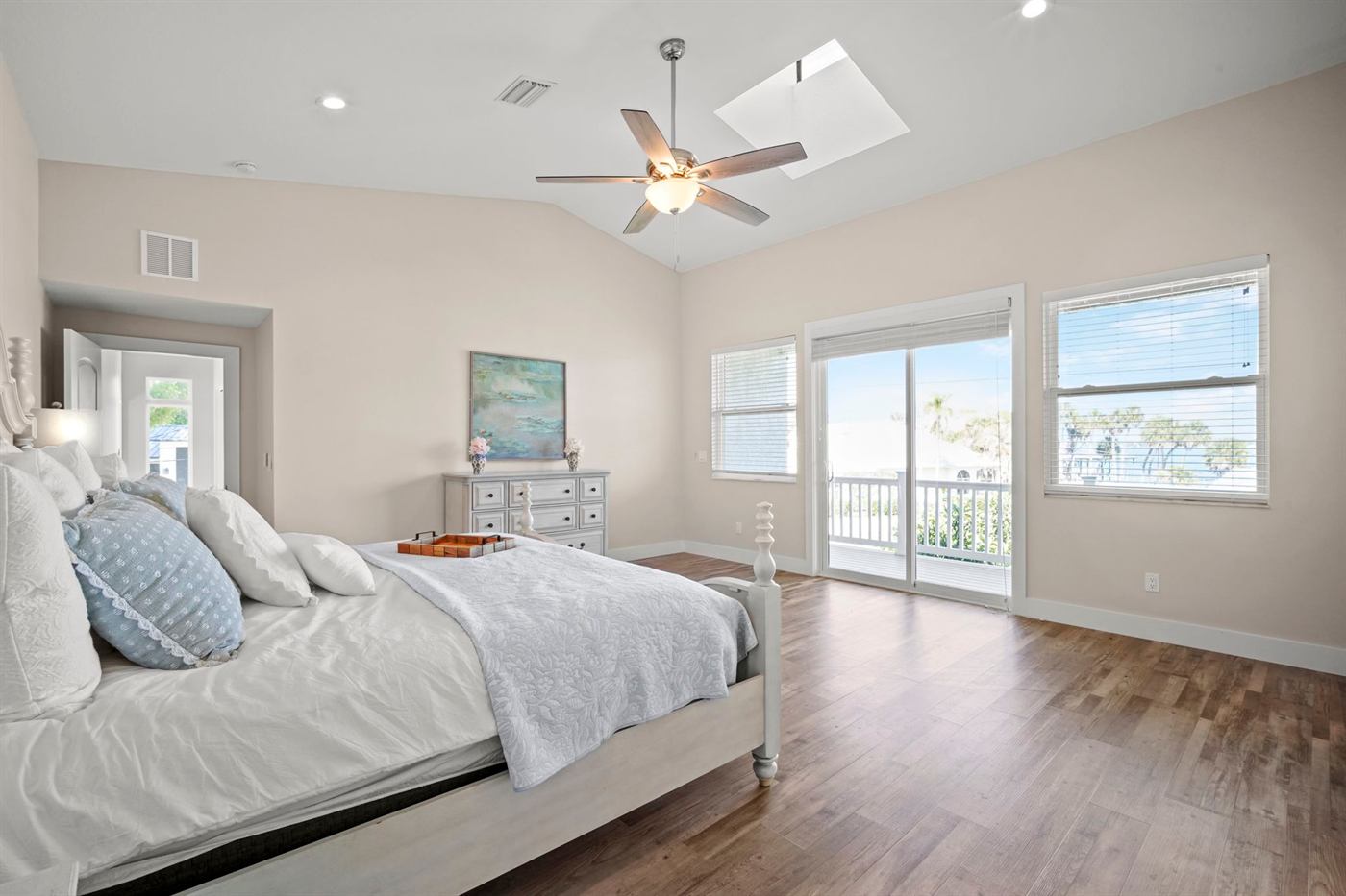 Primary bedroom with vaulted ceiling and balcony access