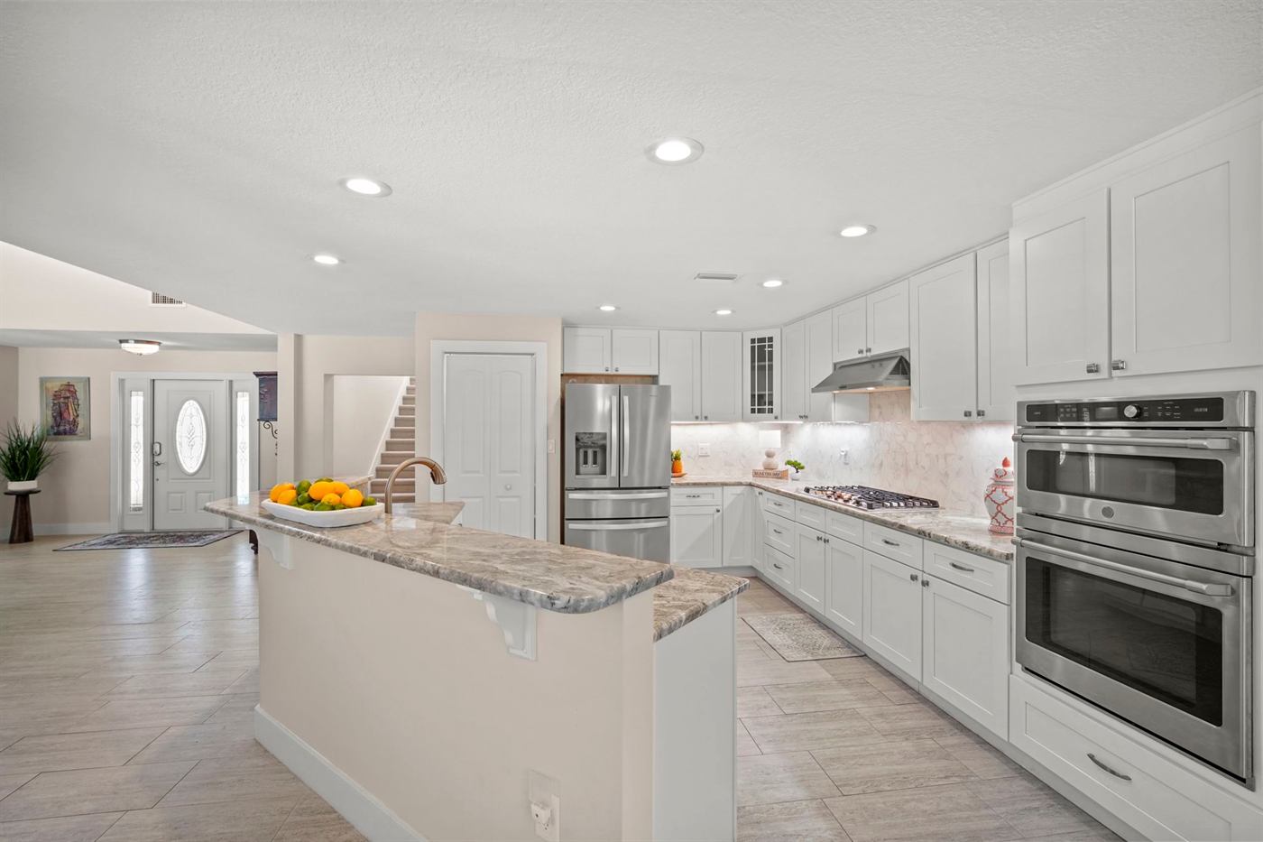 Renovated white kitchen with stone island and stainless appliances